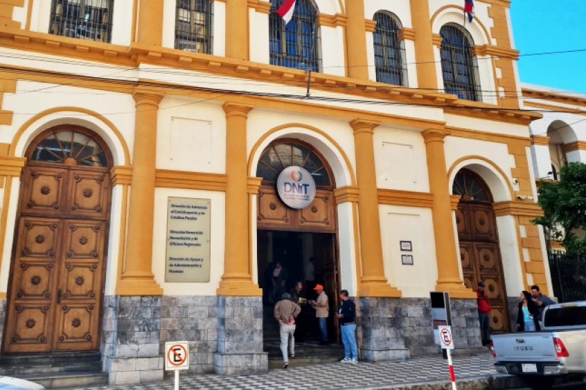 Historisches Verwaltungsgebäude der Dirección Nacional de Ingresos Tributarios (DNIT) in Asunción, orange-weiße Fassade mit drei Holztüren und DNIT-Schild über dem mittleren Eingang