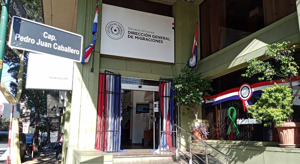 Eingang des früheren Gebäudestandorts der paraguayischen Migrationsbehörde an der Ecke Caballero/Eligio Ayala in Asunción, mit Behördenbeschilderung und paraguayischen Farben